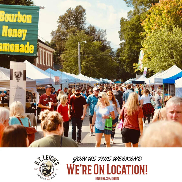 Crowd at outdoor arts festival with vendor tents, B.T. Leigh's Sauces and Rubs event banner visible.