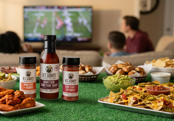 B.T. Leigh's barbecue sauces on a sports-themed table with snacks and TV in the background