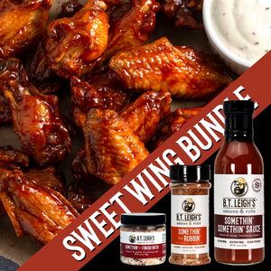 Bowl of wings with B.T. Leigh's sauce and seasoning bottles on a brown background.
